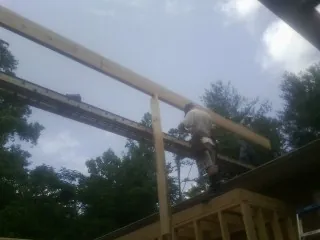 Carpenter setting a ridge beam over a new addition frame — Ice Dam Removal by Roofing Brothers in Empire