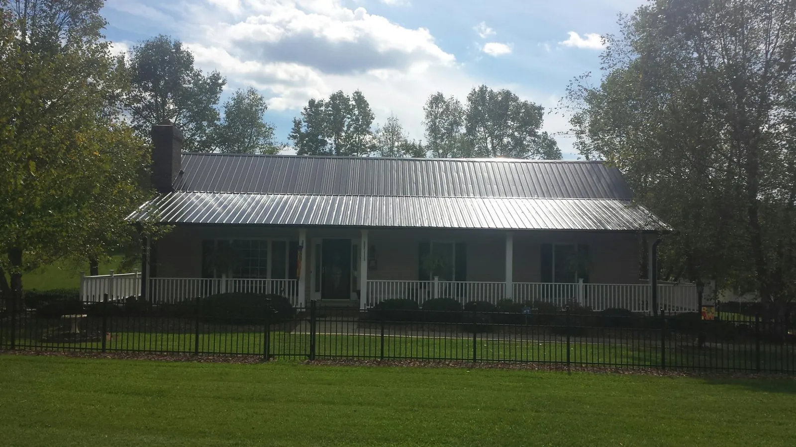 Gray metal roof on a brick ranch with a full width front porch — Gutter Guard Installation work by our crew in Empire